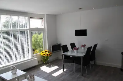 a dining room with a table and chairs and a window at Appartement De Zeester in Zandvoort