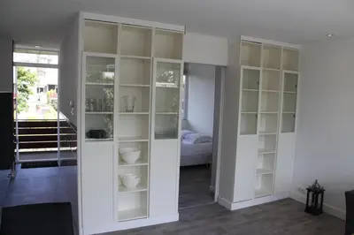 a living room with white cabinets and a bed at Appartement De Zeester in Zandvoort