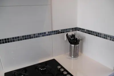 a kitchen counter with a stove and a cup of utensils at Appartement De Zeester in Zandvoort