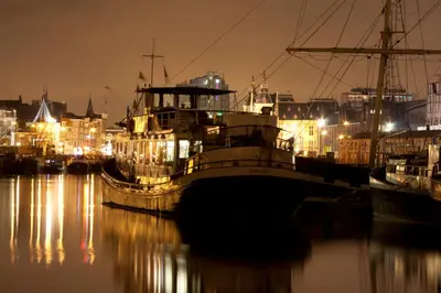 a large boat docked in a harbor at night at Vita Nova in Amsterdam