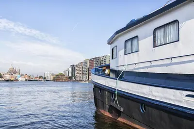 a boat sitting in the water next to a city at Vita Nova in Amsterdam