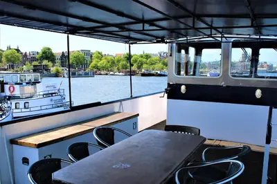 a table and chairs on a boat in the water at Vita Nova in Amsterdam