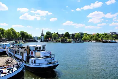 two boats are docked on a river in a city at AmicitiA in Amsterdam