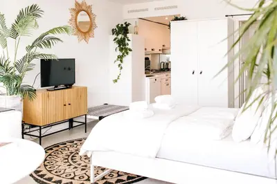 a white living room with a white couch and a tv at Studio at Sea in Zandvoort