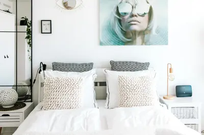 a bedroom with white bedding and a portrait of a woman at Studio at Sea in Zandvoort