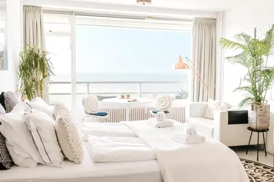 a living room with a white couch with pillows at Studio at Sea in Zandvoort
