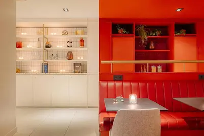 a dining room with a red booth with a table at Leonardo Eden Hotel Amsterdam City Center in Amsterdam