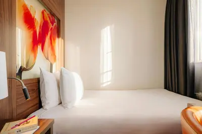 a bedroom with a white bed with a window at Leonardo Eden Hotel Amsterdam City Center in Amsterdam