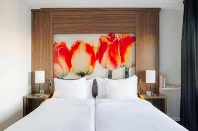 two beds in a hotel room with flowers on the wall at Leonardo Eden Hotel Amsterdam City Center in Amsterdam