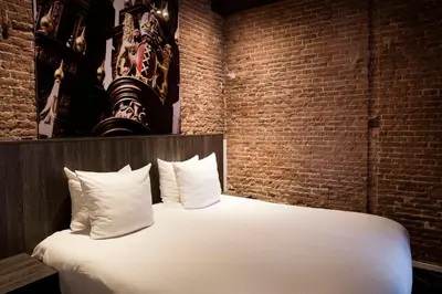 a large bed in a room with a brick wall at Leonardo Eden Hotel Amsterdam City Center in Amsterdam