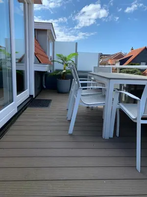 a deck with a table and chairs on a balcony at Vakantiehuis Witsand 1 in Egmond aan Zee