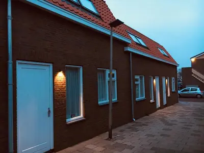 a brick building with a white door on the side at Vakantiehuis Witsand 1 in Egmond aan Zee