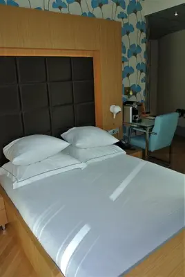a large white bed in a room with a chair at Amadi Park Hotel in Amsterdam