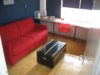 a living room with a red couch and a red chair at De Krasse Man in Edam