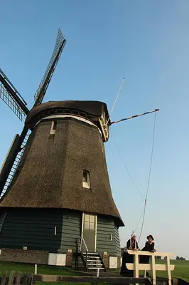 two people sitting on a bench in front of a windmill at De Krasse Man in Edam