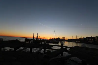 a sunset over a dock with benches and the water at De Krasse Man in Edam