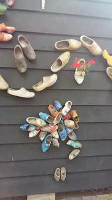 a bunch of pairs of shoes on a wall at Me Oissie in Egmond aan Zee