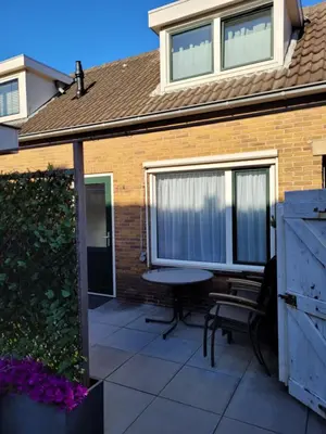 a patio with a table and chairs in front of a house at Sauna Cottage Egmond in Egmond aan Zee