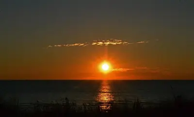a sunset over the ocean with the sun in the sky at Sauna Cottage Egmond in Egmond aan Zee