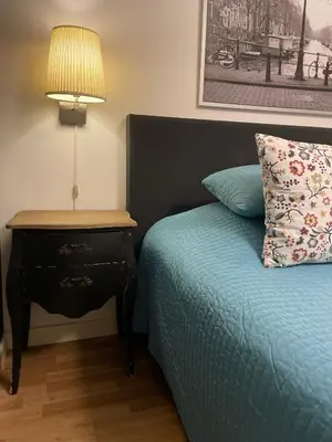 a bedroom with a bed and a nightstand with a lamp at Artist House Amsterdam in Amsterdam