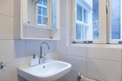 a white bathroom with a sink and two windows at Artist House Amsterdam in Amsterdam