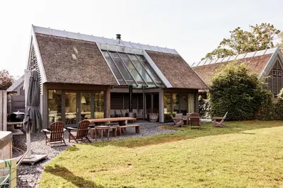 a house with a table and chairs in the yard at Dutchen Vakantiepark Duynvoet in Schoorl
