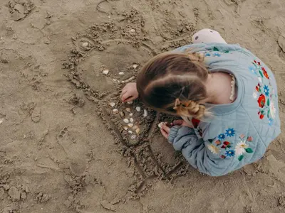 a little girl drawing a heart in the sand at Dutchen Vakantiepark Duynvoet in Schoorl