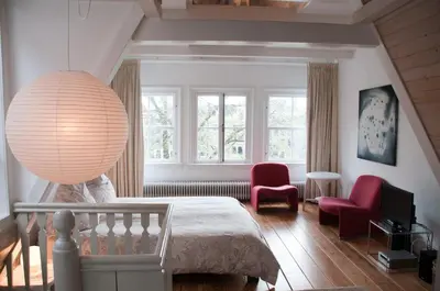 a living room with a bed and a pendant light at Kalkmarkt Suites in Amsterdam