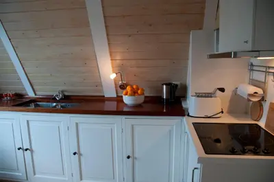 a kitchen with white cabinets and a bowl of oranges at Kalkmarkt Suites in Amsterdam