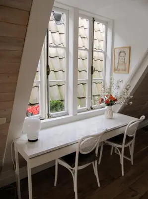 a dining room with a white table and two windows at Kalkmarkt Suites in Amsterdam