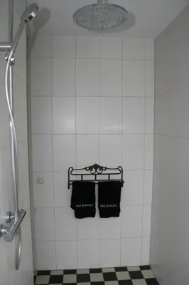 a bathroom with two black towels hanging on a wall at B&B Het kasteel in Almere
