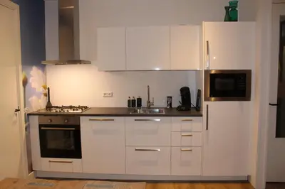 a kitchen with white cabinets and a refrigerator at Appartement 4 Seasons Katwijk aan Zee in Katwijk aan Zee