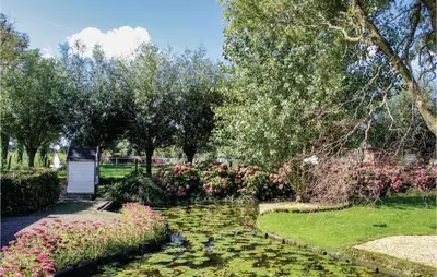 a garden with a pond with flowers and trees at Hoeve Alegria in Hoogwoud