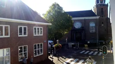 a large brick building with a clock tower and a church at Zoetermeer City Center Loft Apartment in Zoetermeer