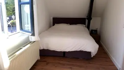 a bed in a small room with a window at Zoetermeer City Center Loft Apartment in Zoetermeer