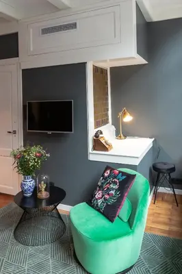 a living room with a green chair and a table at The Blossom House Amsterdam in Amsterdam