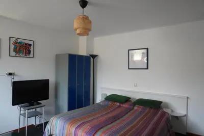a bedroom with a bed and a television at villa Flore, studio's in Bergen aan Zee