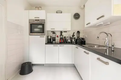 a white kitchen with white cabinets and a sink at Cozy room in residential Alkmaar - Free parking in Alkmaar