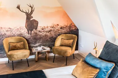 a living room with two chairs and a painting of a deer at de Vogelensangh in Vogelenzang