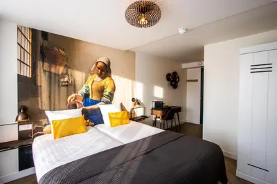 a woman sitting on a bed in a room at Hotel Neptunus in Egmond aan Zee