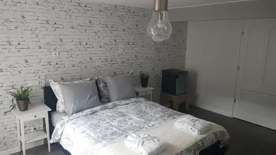 a white bedroom with a bed and a tv at B&B de Valkenhorst in Lelystad