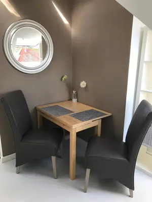 a dining room table with two chairs and a mirror at Pension Corper in Zandvoort