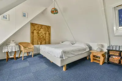 a bedroom with a bed and a table and a chair at B&B De Duinhoek in Beverwijk