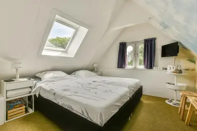 a bedroom with a large bed and a window at B&B De Duinhoek in Beverwijk