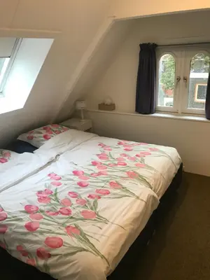 a bedroom with a bed with flowers on it at B&B De Duinhoek in Beverwijk
