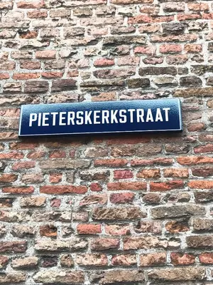 a sign on the side of a brick wall at De Pelgrimsplaats in Leiden