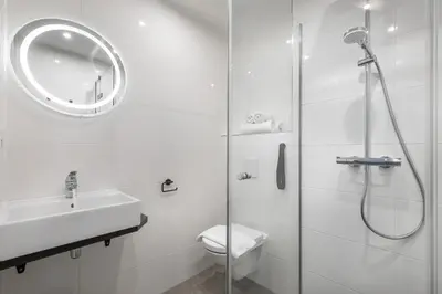 a bathroom with a shower and a toilet and a sink at Hotel New Kit in Amsterdam