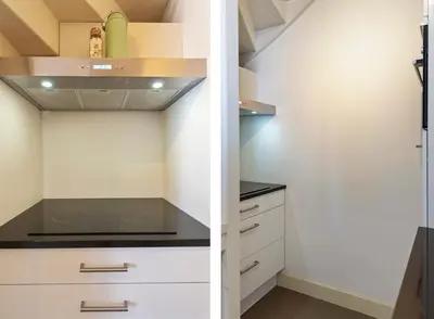 a kitchen with white cabinets and a staircase at Flamingo Beach Apartments in Zandvoort