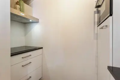 a kitchen with white cabinets and a refrigerator at Flamingo Beach Apartments in Zandvoort