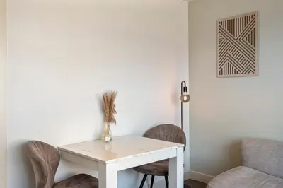 a white table with chairs and a white wall at Flamingo Beach Apartments in Zandvoort